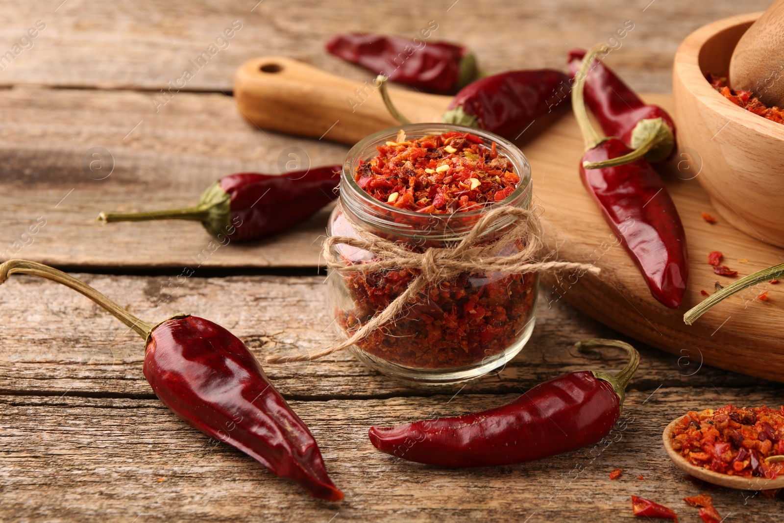 Photo of Chili pepper flakes and pods on wooden table