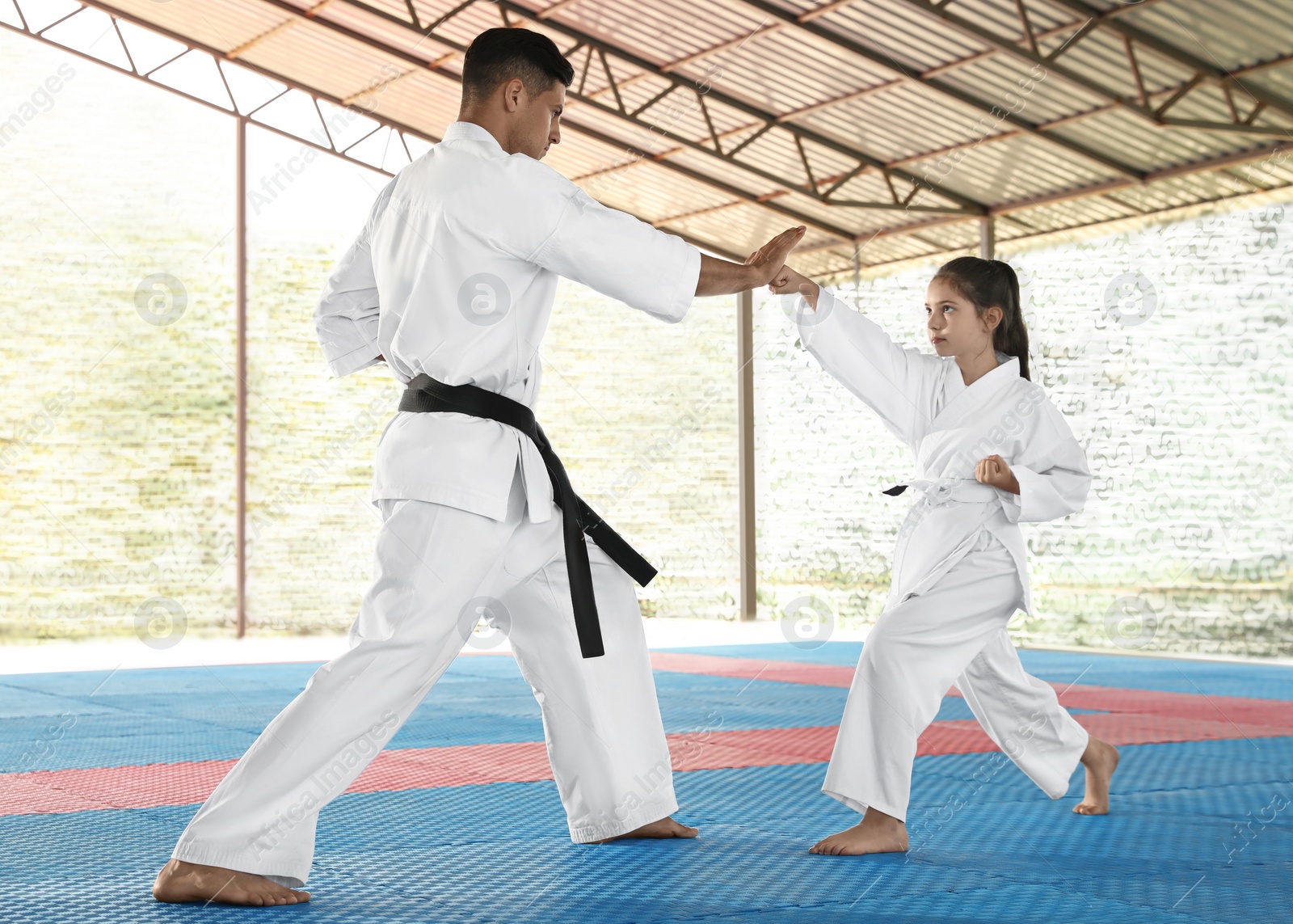 Photo of Girl practicing karate with coach on tatami outdoors