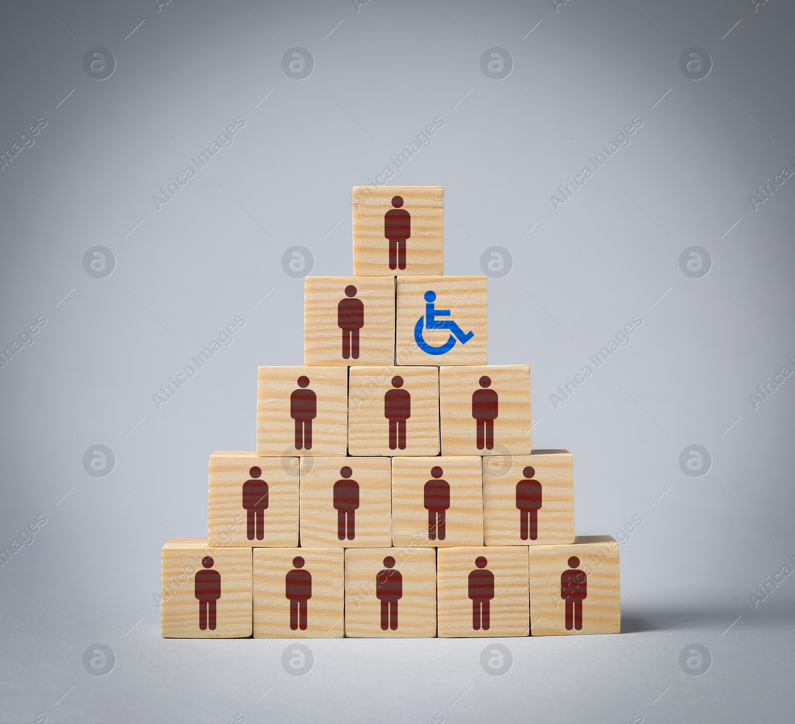 Image of Inclusive workplace culture. Pyramid of wooden cubes with human icons and one with international symbol of access on grey background