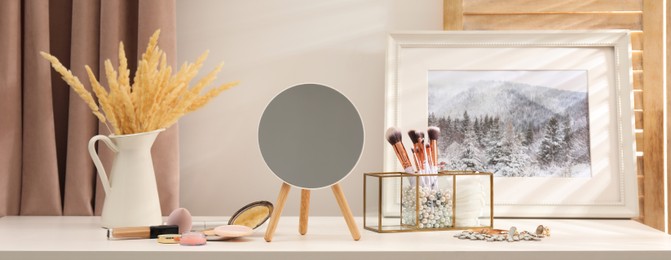 Makeup room. Mirror, cosmetic products and jewelry on dressing table indoors, banner design