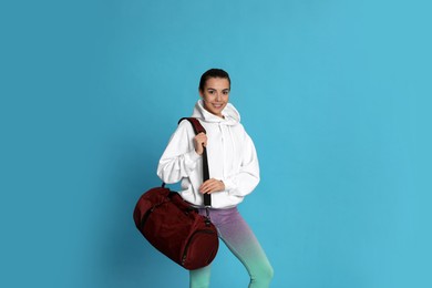 Photo of Beautiful woman with sports bag on light blue background