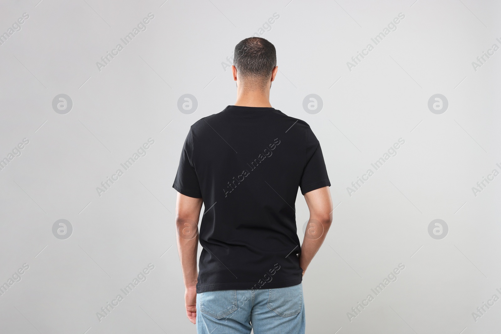 Photo of Man wearing black t-shirt on gray background, back view