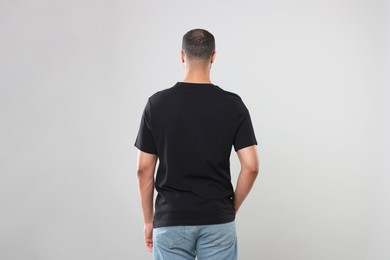 Man wearing black t-shirt on gray background, back view
