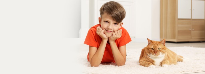 Image of Little boy and cute ginger cat on soft carpet at home. Banner design with space for text