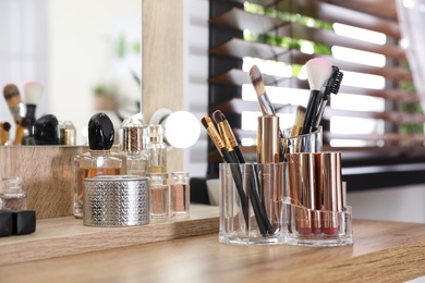 Photo of Makeup products and accessories on dressing table against blurred background