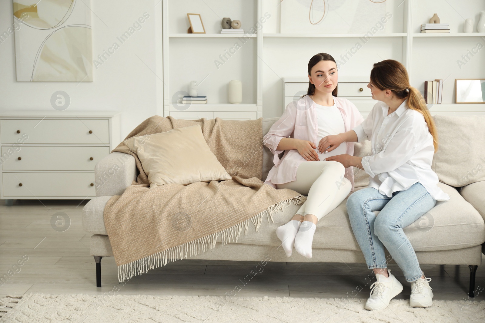 Photo of Doula taking care of pregnant woman on sofa at home. Preparation for child birth