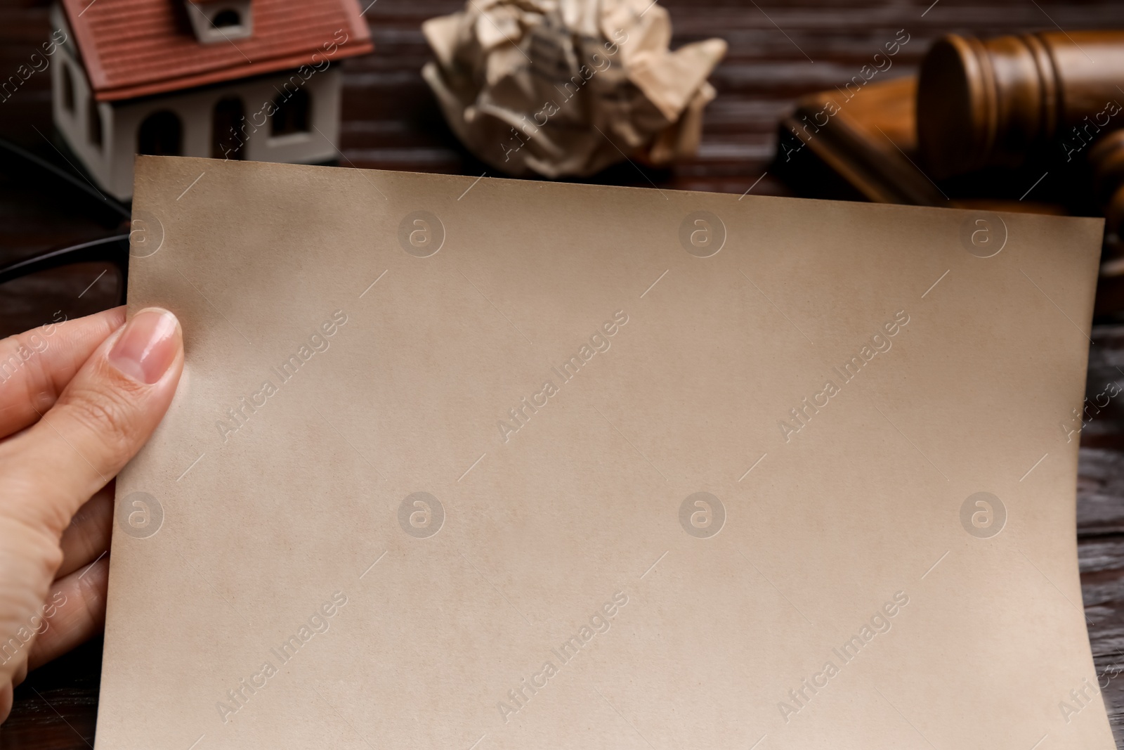 Photo of Woman holding last will and testament at wooden table, closeup