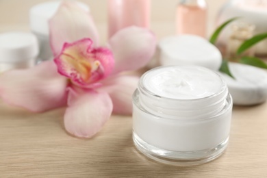 Photo of Beautiful spa composition with cosmetic product and flower on table, closeup
