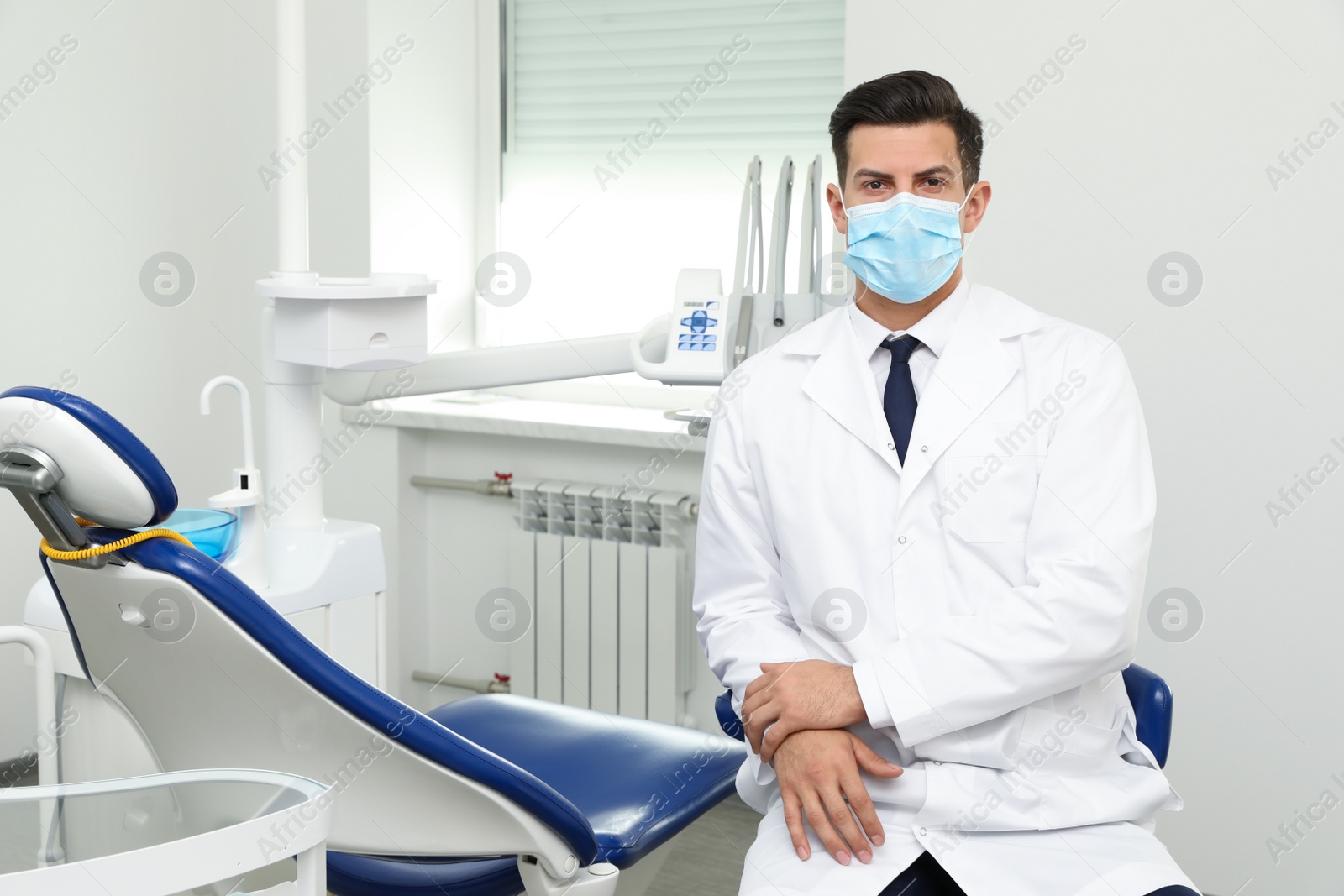 Photo of Portrait of professional male dentist in clinic. Space for text