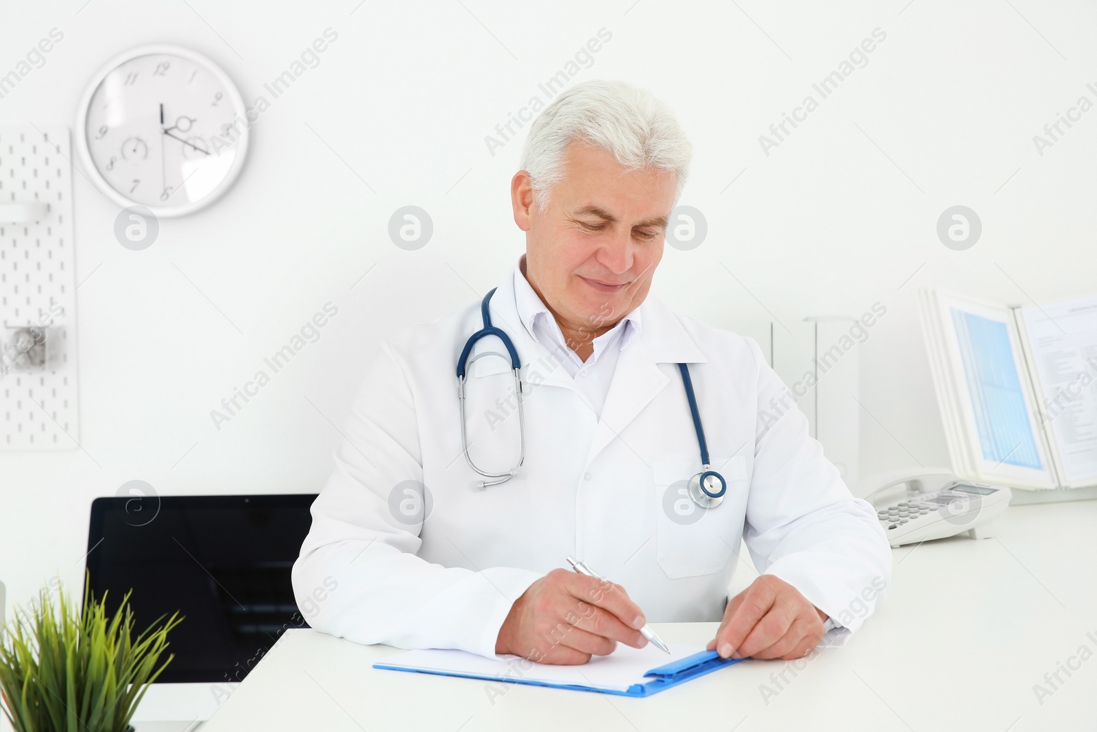 Photo of Senior male doctor working at reception desk in hospital