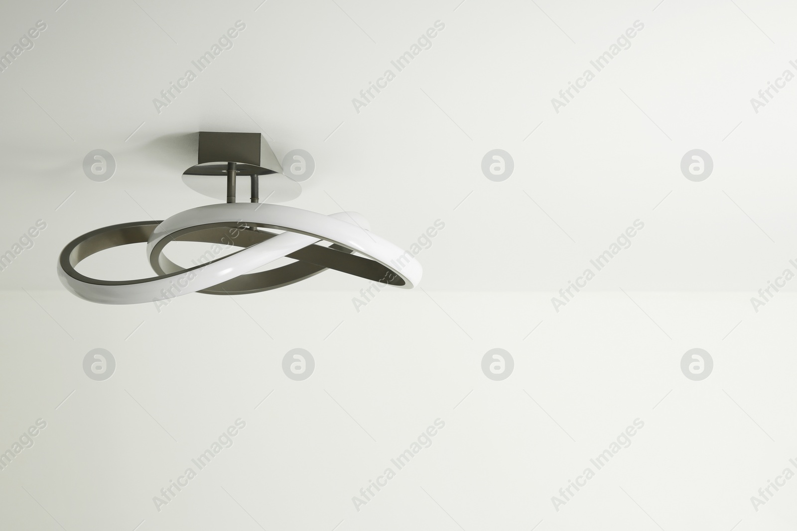 Photo of Stylish lamp on white ceiling. Space for text