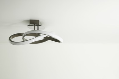 Stylish lamp on white ceiling. Space for text