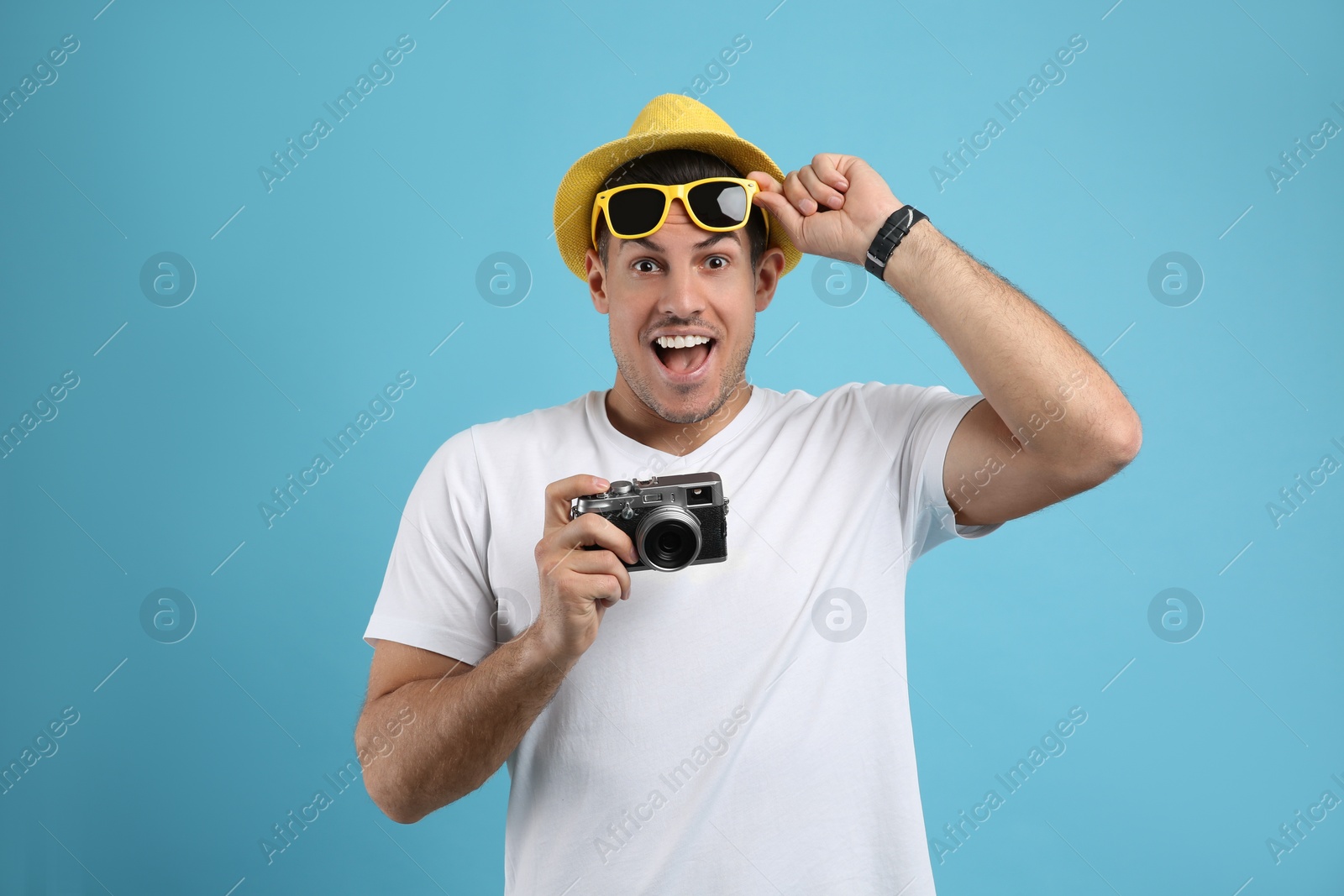 Photo of Excited male tourist with camera on turquoise background