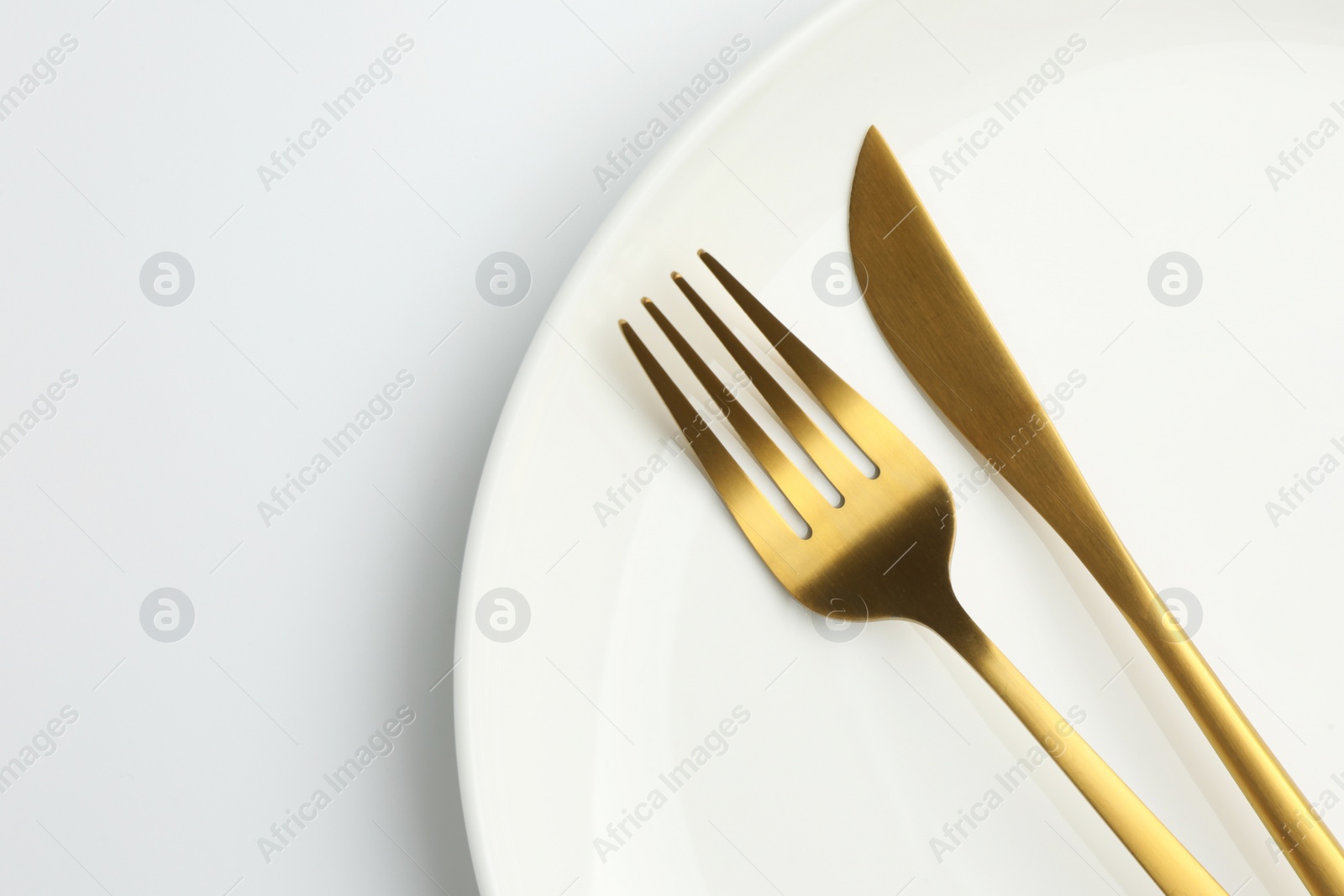 Photo of Plate, fork and knife on white background, top view. Space for text