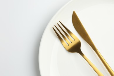 Plate, fork and knife on white background, top view. Space for text