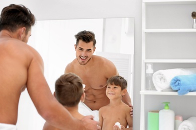 Father and son having fun while applying shaving foam in bathroom