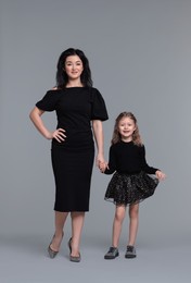 Beautiful mother with little daughter on grey background