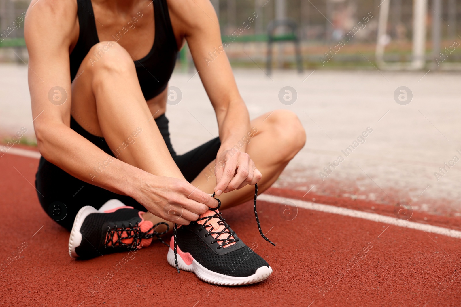 Photo of Woman tying shoelaces before training outdoors. closeup. Space for text