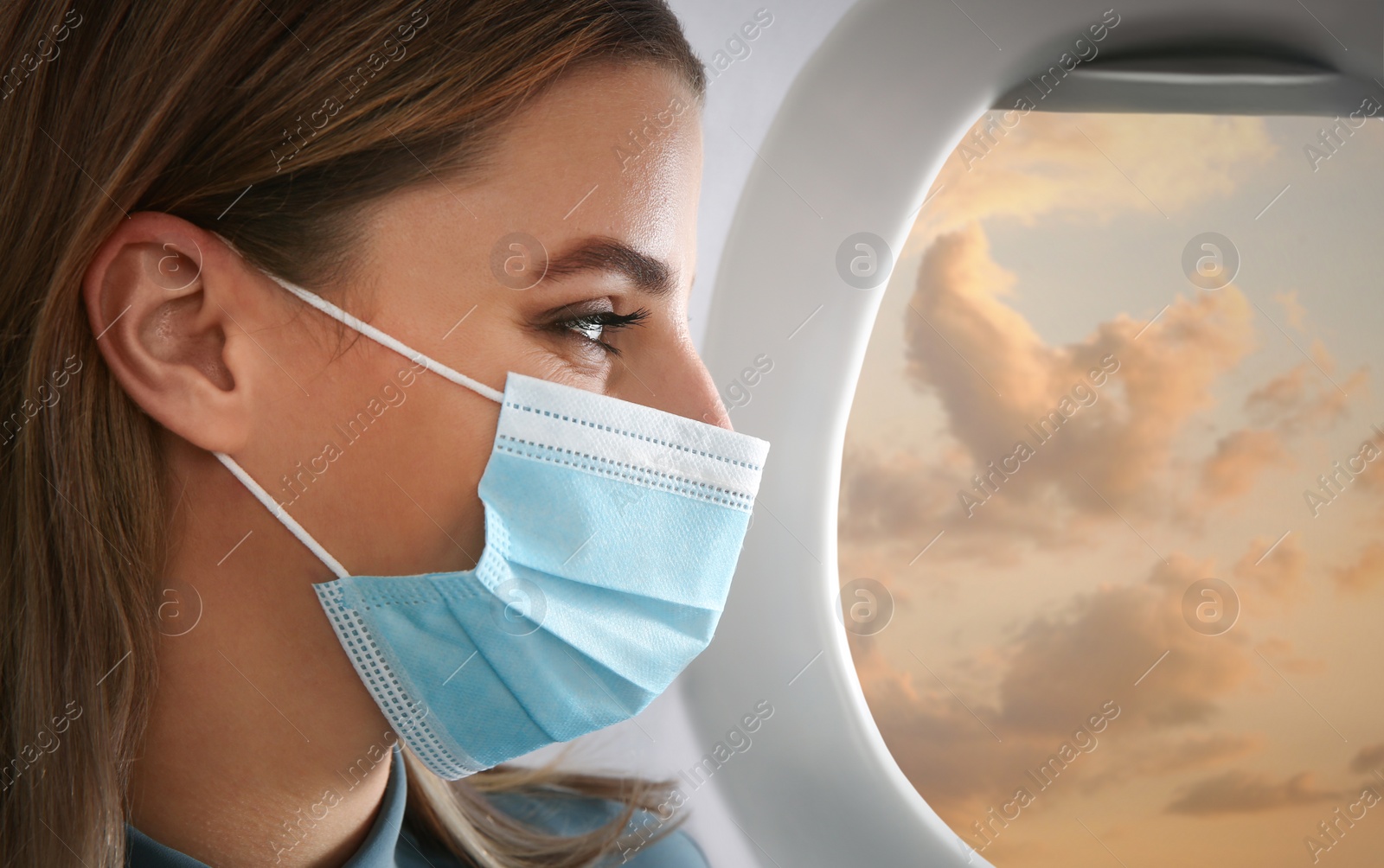 Image of Traveling by airplane during coronavirus pandemic. Woman with face mask near porthole