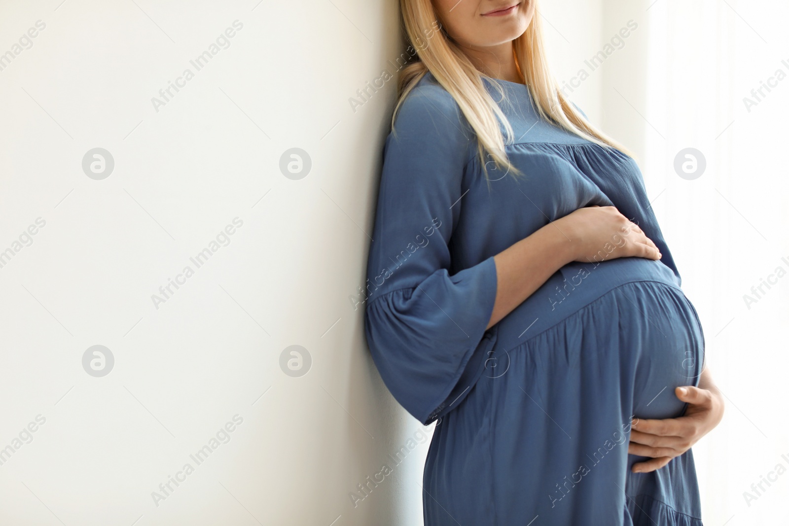 Photo of Pregnant woman on light background, closeup. Space for text