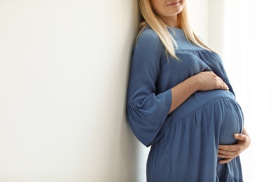 Photo of Pregnant woman on light background, closeup. Space for text