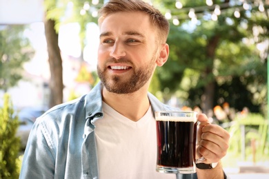 Photo of Handsome man with cold kvass outdoors. Traditional Russian summer drink