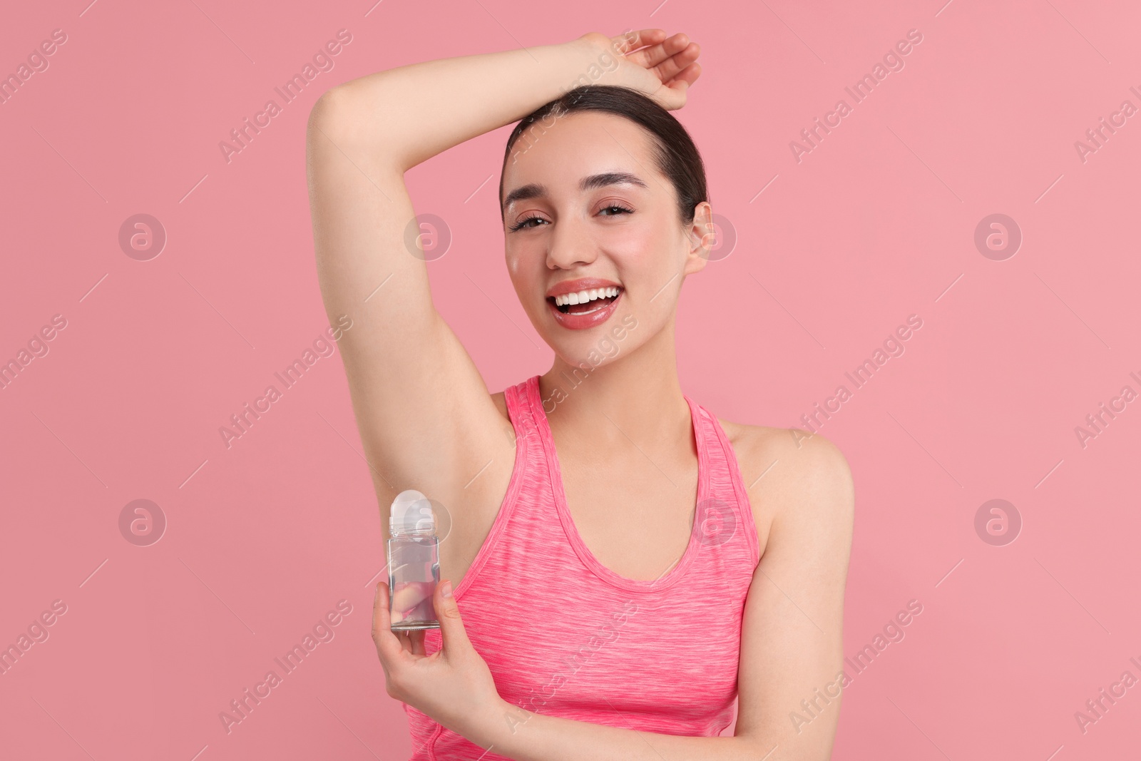 Photo of Beautiful woman applying deodorant on pink background