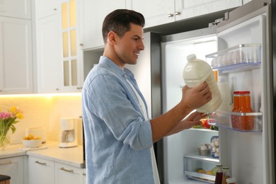 Man putting gallon of milk into refrigerator in kitchen