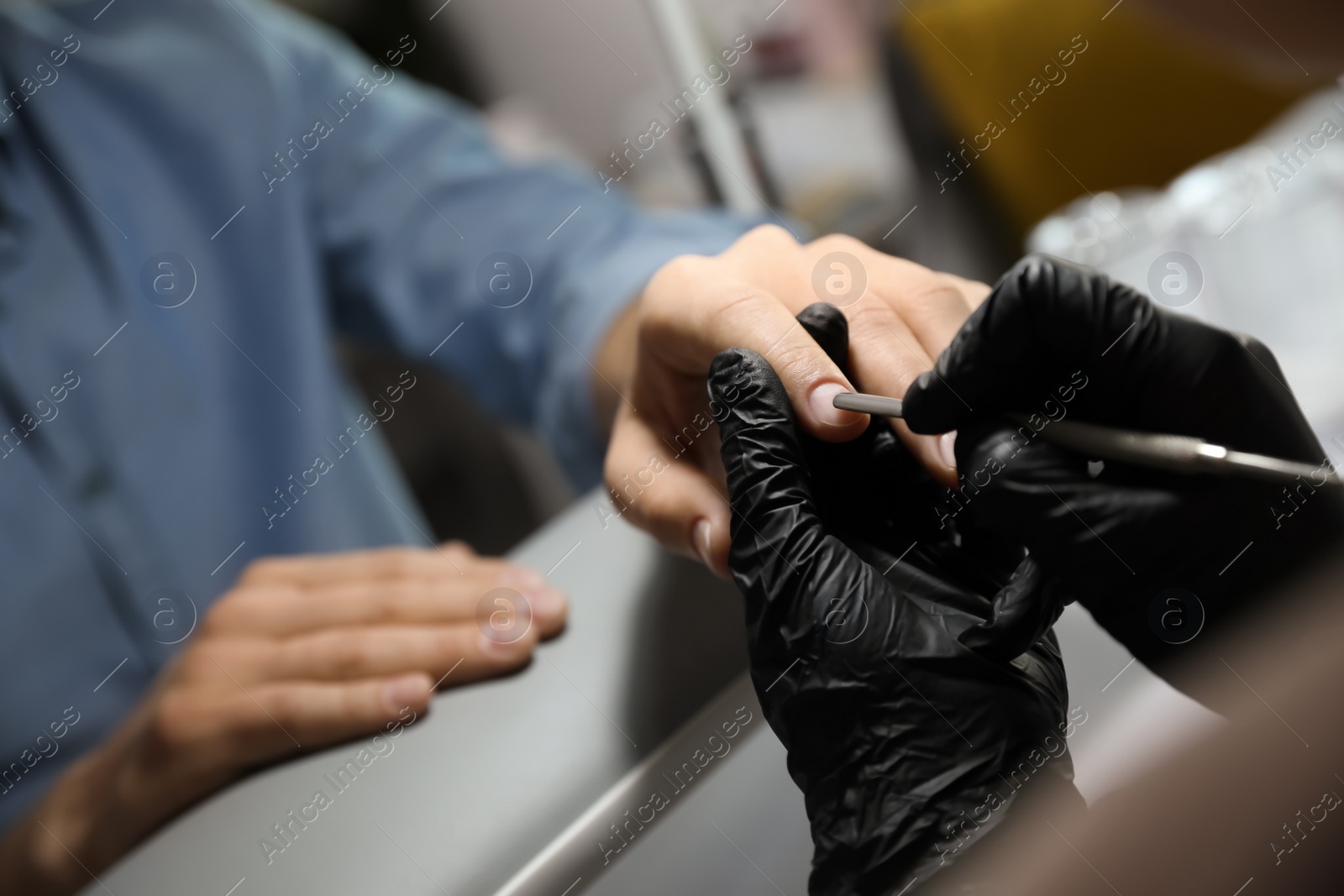 Photo of Professional manicurist working with client in beauty salon, closeup