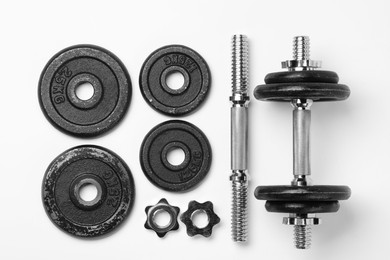Photo of Metal dumbbell and parts on white background, top view. Sports equipment