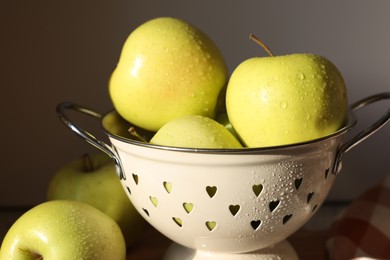 Photo of Fresh wet apples in colander on dark background, closeup