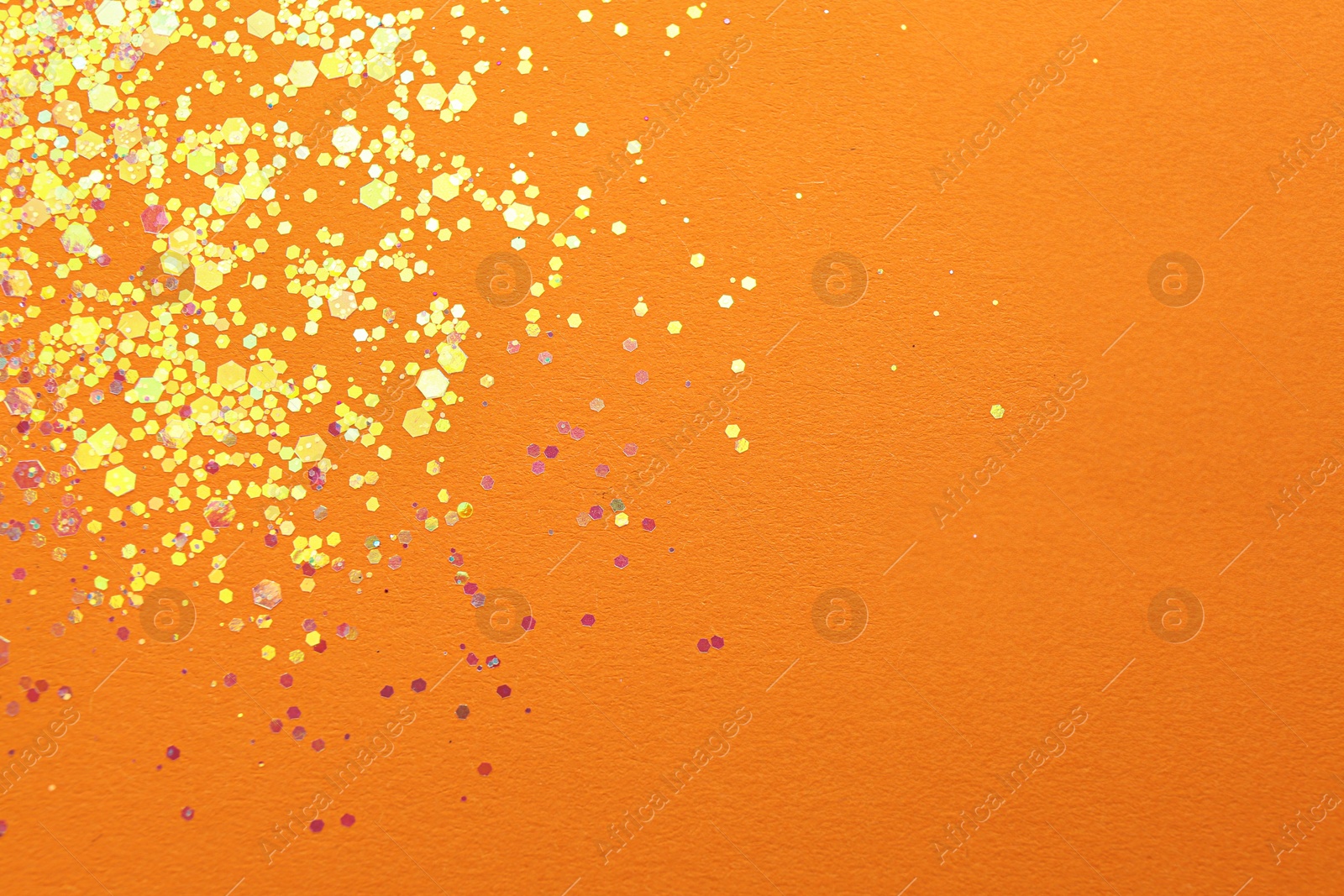 Photo of Shiny bright golden glitter on orange background, flat lay. Space for text