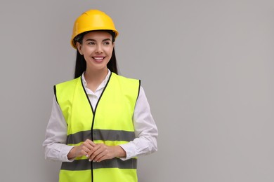 Engineer in hard hat on grey background, space for text