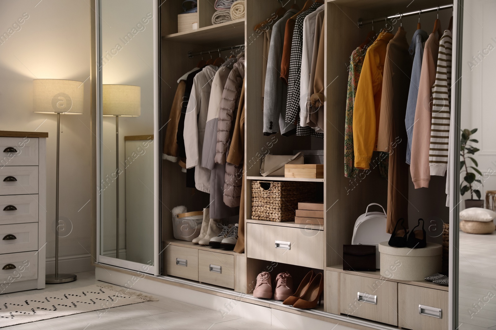 Photo of Wardrobe closet with different stylish clothes, shoes and home stuff in room