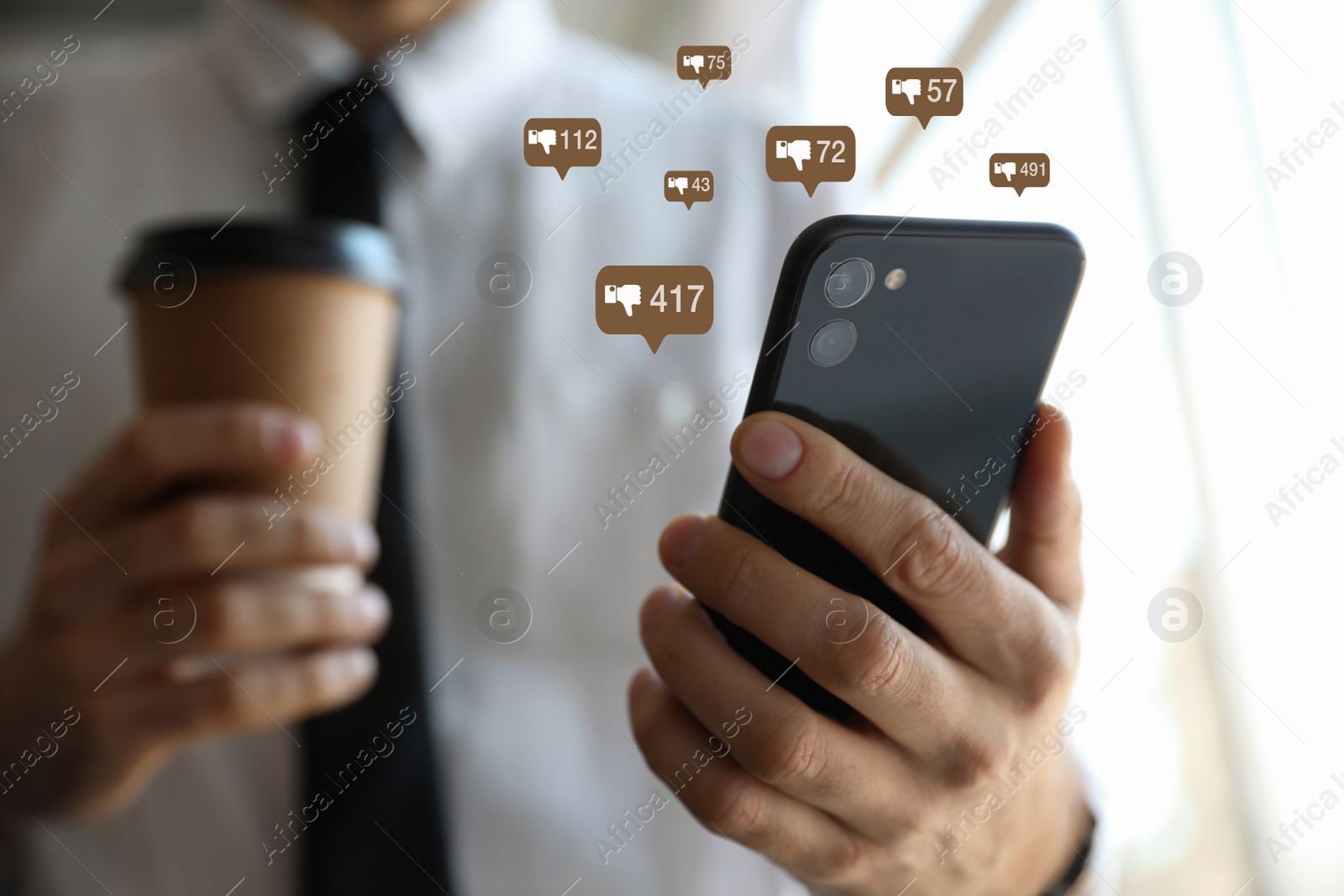 Image of Closeup view of young man using modern smartphone indoors and virtual dislike icons. Cyberbullying concept