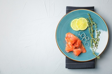 Photo of Plate with fresh sliced salmon fillet, lemon and thyme on light background, top view