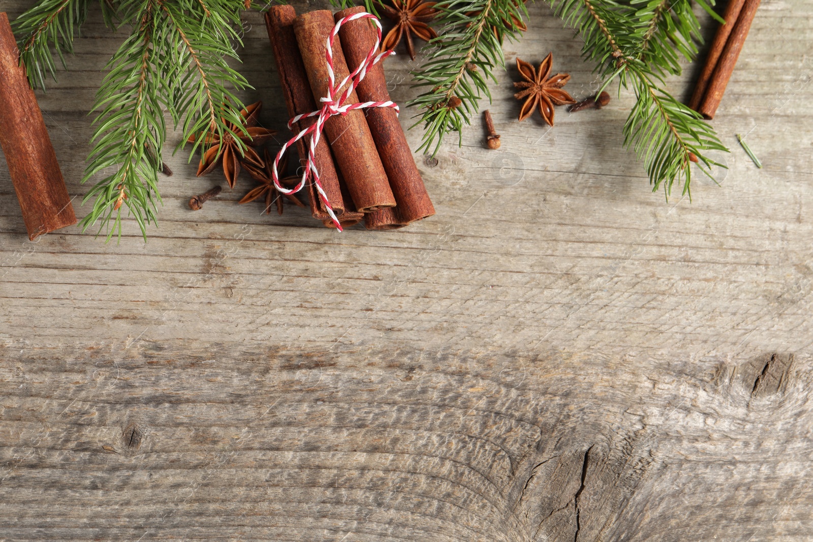 Photo of Different spices and fir branches on wooden table, flat lay. Space for text