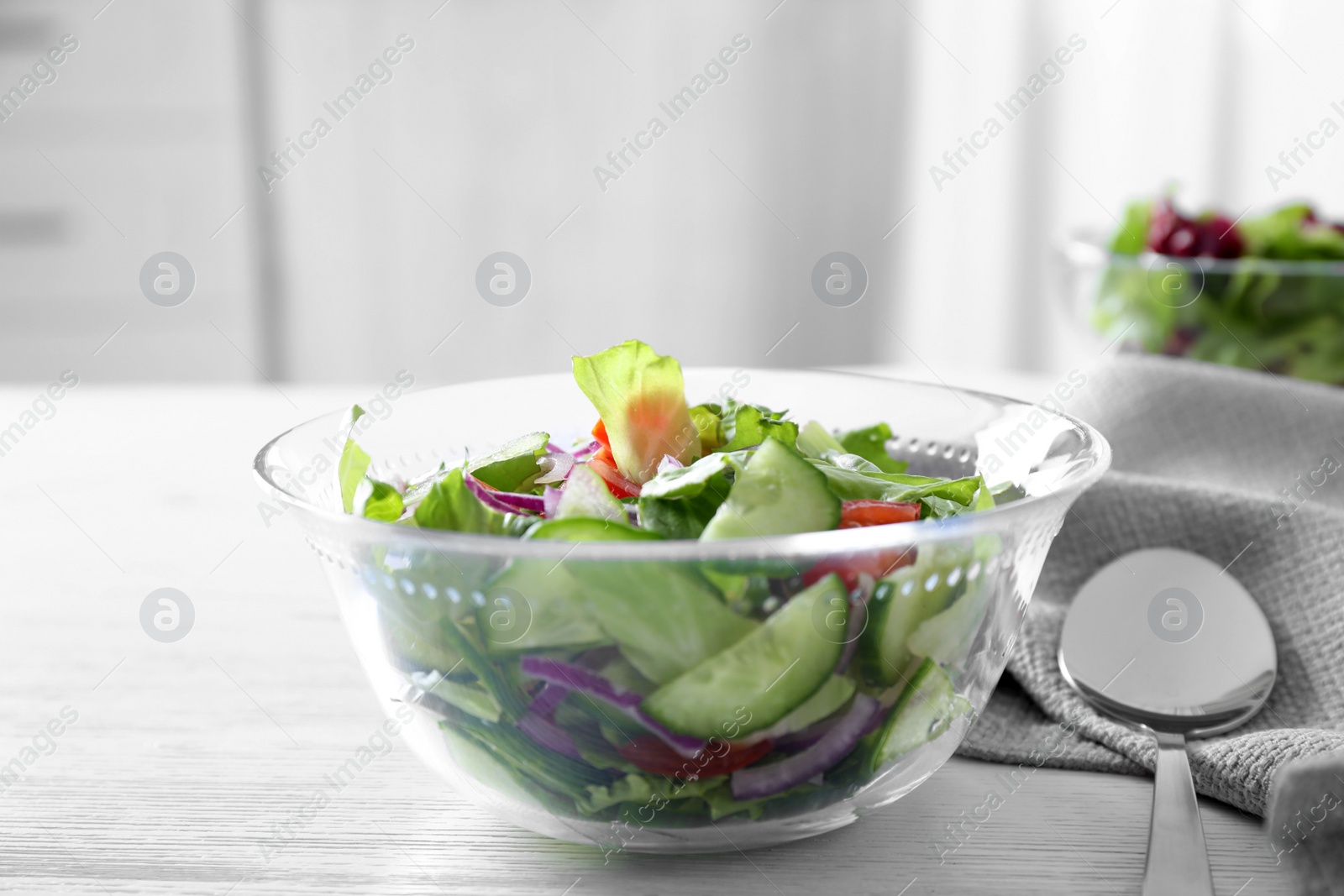 Photo of Bowl of tasty salad with cucumber and lettuce on table