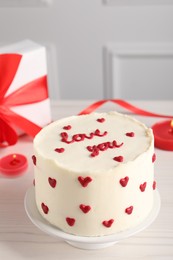 Bento cake with text Love You, candles and gift box on white wooden table. St. Valentine's day surprise