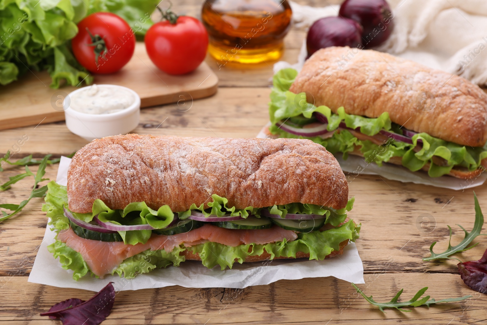 Photo of Delicious sandwiches with fresh vegetables and salmon on wooden table