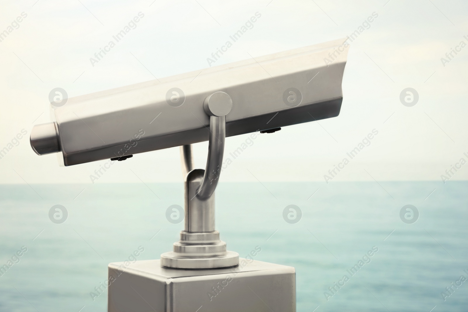 Photo of Metal tower viewer installed near sea. Mounted binoculars