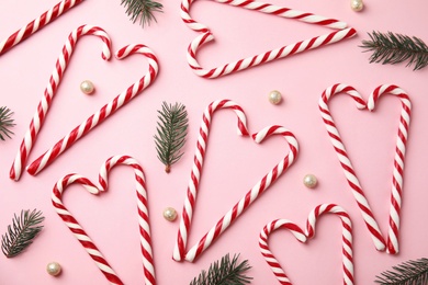 Flat lay composition with candy canes and fir tree branches on pink background