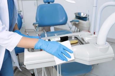 Photo of Professional dentist in white coat cleaning workplace indoors, closeup