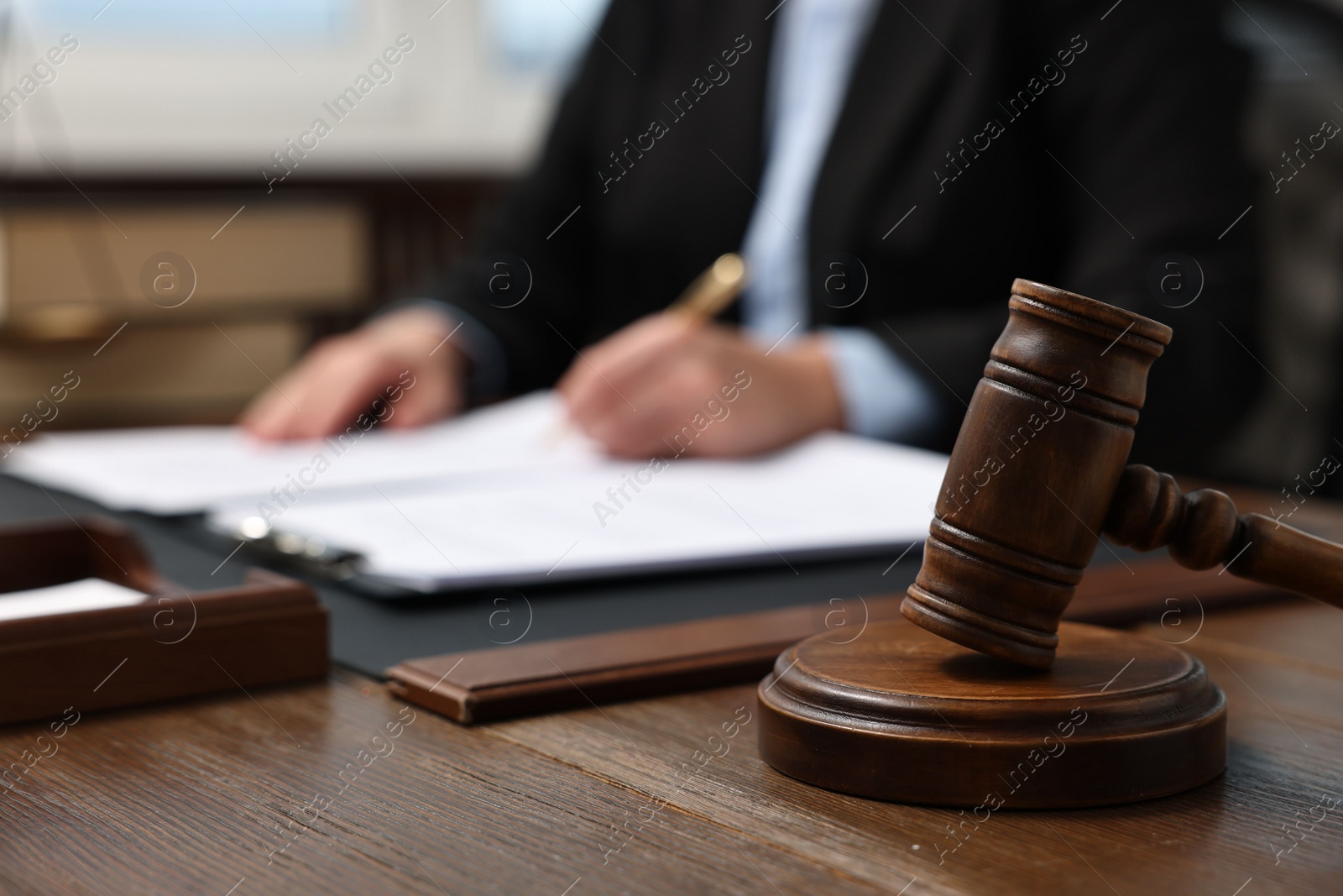 Photo of Lawyer working with documents at wooden table indoors, focus on gavel