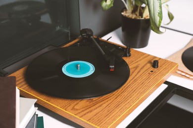Photo of Stylish turntable with vinyl disc near grey wall in room, closeup
