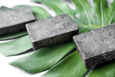 Photo of Natural tar soap and green leaf on table, closeup