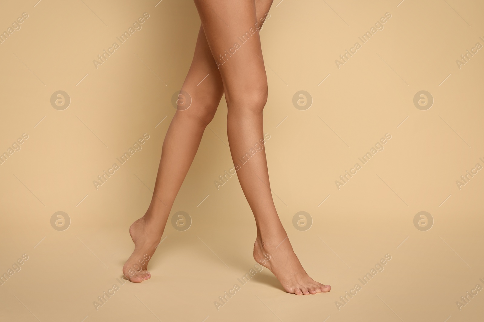 Photo of Woman with beautiful long legs on beige background, closeup
