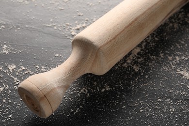 Photo of Scattered flour and rolling pin on dark textured table, closeup