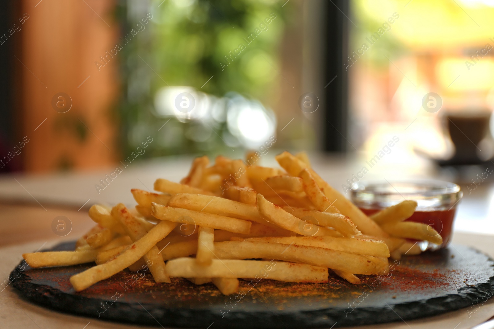 Photo of Delicious hot french fries with red sauce served on table, closeup