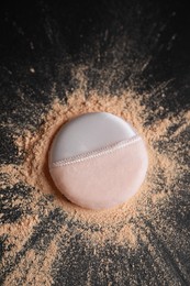 Photo of Puff applicator and loose face powder on black background, flat lay